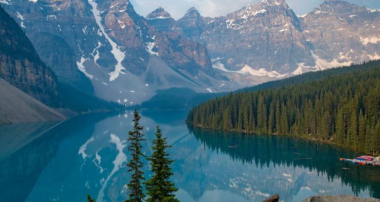 Reflet cristallin des pics enneigés et des sapins denses dans les eaux calmes du lac Moraine.