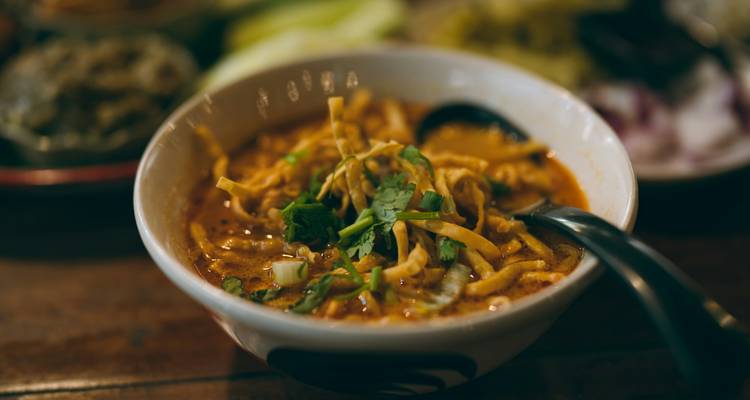 Gros plan d'un bol fumant de soupe de nouilles de curry Khao Soi du nord de la Thaïlande garni de coriandre.