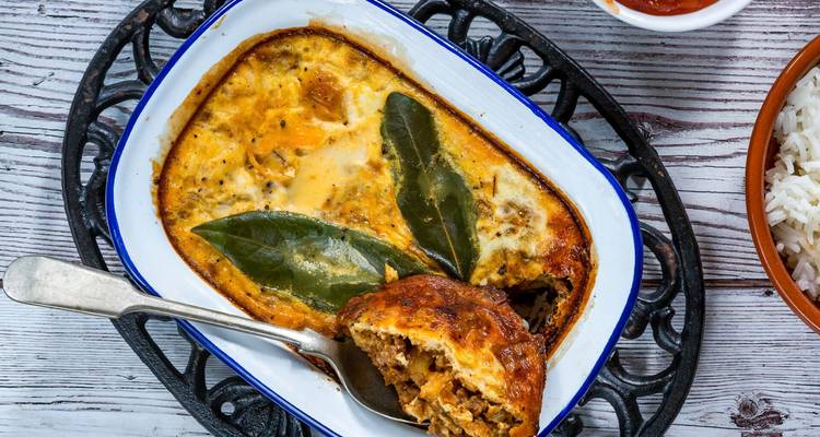 Casserole de bobotie sud-africaine traditionnelle garnie de feuilles de laurier.