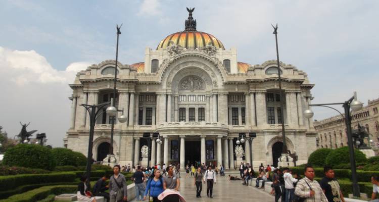 Palacio de Bellas Artes mit orangefarbener Kuppel mit Ziegeldach und Menschenmengen, die sich in den Vorhofgärten versammeln