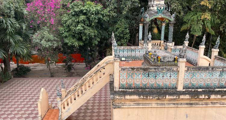 Vista elevada de una tumba u santuario ornamentado con azulejos dentro de un patio de templo frondoso.