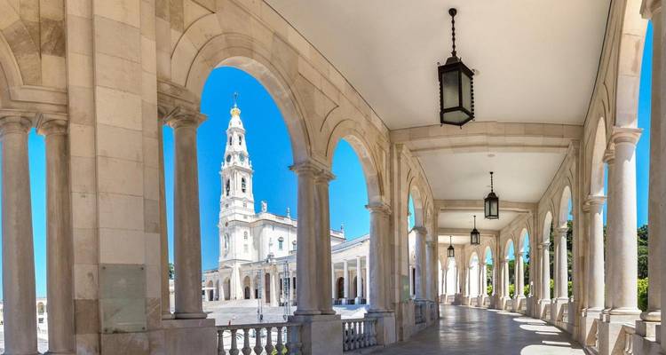Elegant colonnade frames the Basilica of Fátima with brilliant blue skies overhead.