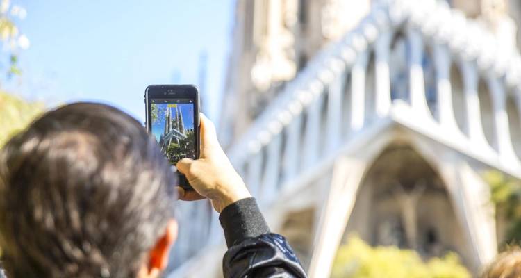 Turista fotografiando las torres de la Sagrada Familia de Barcelona con un smartphone.