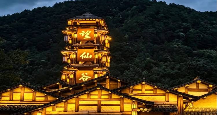 Una pagoda de madera alta brilla cálidamente contra un fondo de montaña boscosa al atardecer.
