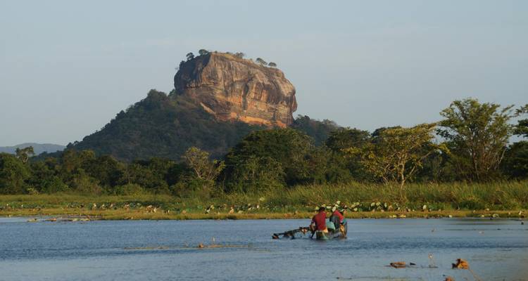Los pescadores vadean por el agua con la Roca de Sigiriya elevándose dramáticamente en el fondo.