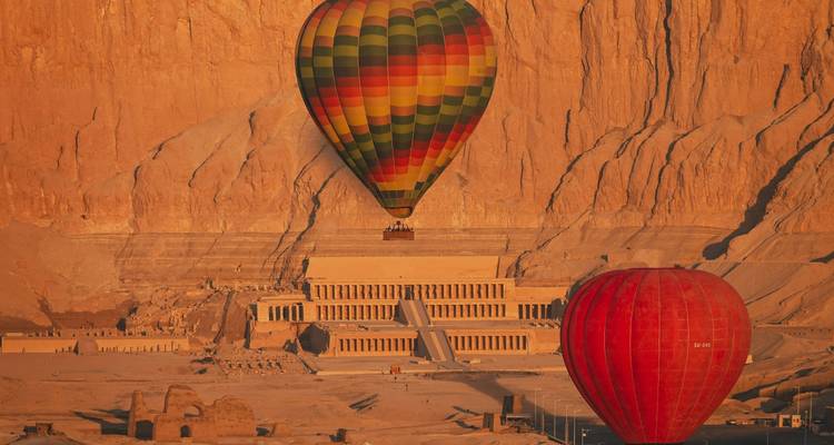 Deux ballons à air chaud flottant au-dessus du Temple d'Hatchepsout baignés dans la lumière chaude du lever de soleil