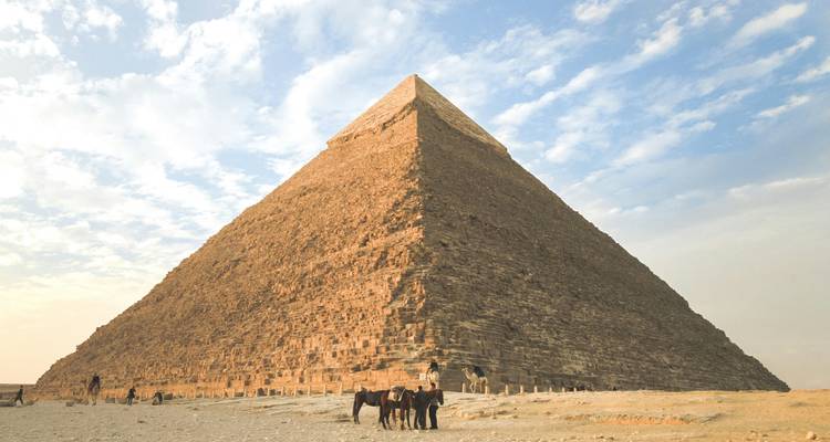 Pyramide dominant une vaste plaine désertique avec des chevaux attendant les cavaliers au premier plan