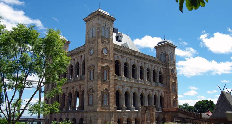 Complejo del palacio Stone Rova con ventanas arqueadas altas en la cima de una colina contra un cielo azul.