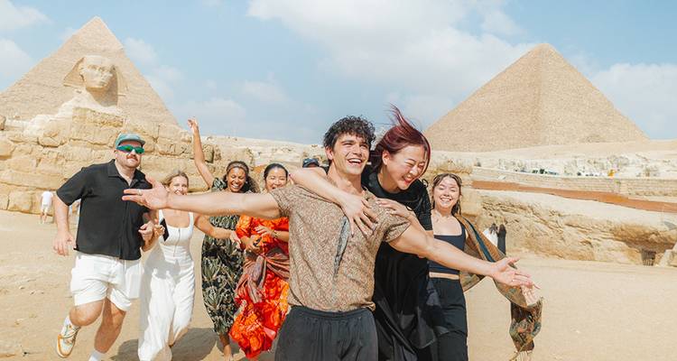 Un groupe joyeux pose devant les Pyramides de Giza et le Sphinx par une journée ensoleillée.