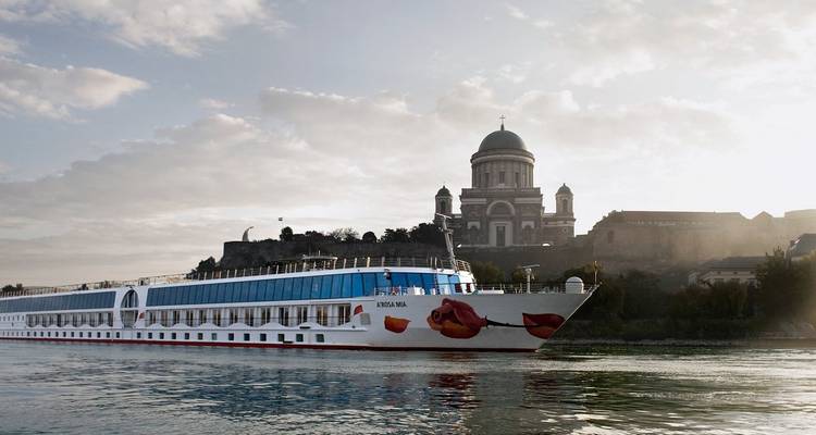 Un bateau de croisière fluviale passe sous la majestueuse Basilique d'Esztergom sous un ciel matinal doux.