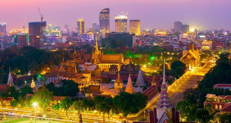 El complejo del Palacio Real de Nom Penh brilla entre el vibrante horizonte de la ciudad al atardecer.