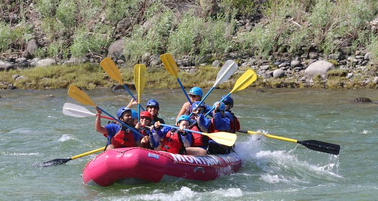 Équipe de rafting en eaux vives levant les pagaies triomphalement sur une rivière au cours rapide