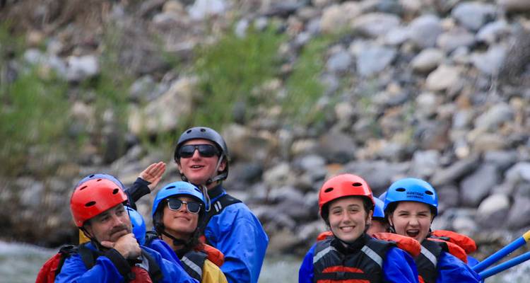Primer plano de remeros con cascos sonriendo y salpicando en un rápido del río