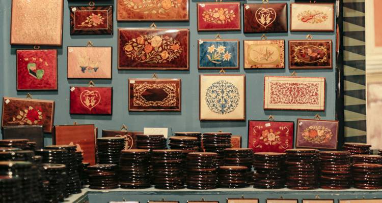 Uitstalling van handgemaakte houten inlegkraslappen en kleurrijk marqueteriekunstwerk in een winkel.