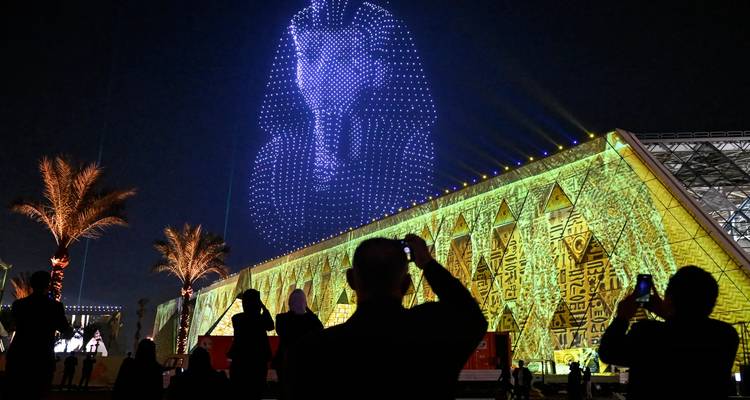 Spectacle nocturne de lumières par drones d'une tête de pharaon au-dessus de la facade du musée illuminée