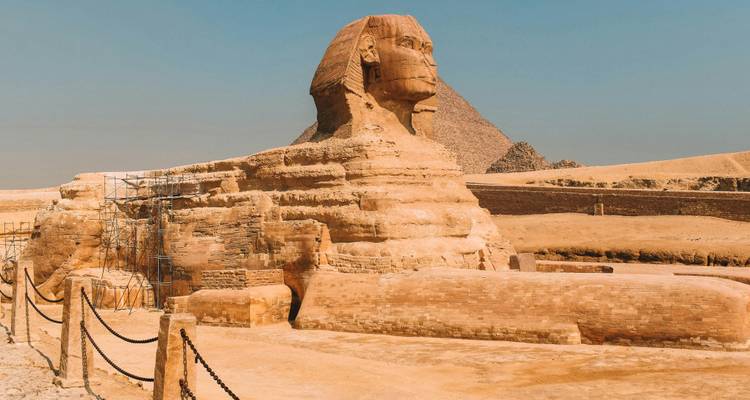 Profil latéral du Grand Sphinx avec la pyramide de Khafré se dressant dans l'arrière-plan brumeux.