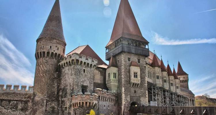 Enorme castillo gótico de Corvin con torres rojas bajo el brillante cielo azul de Transilvania