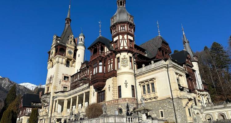 Elegante Castillo de Peleș de estilo Neo-Renacentista enmarcado por un cielo alpino cristalino