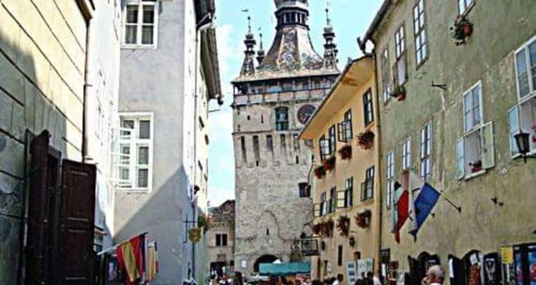 Calle estrecha abarrotada de visitantes dirigiéndose hacia la torre del reloj de Sighisoara