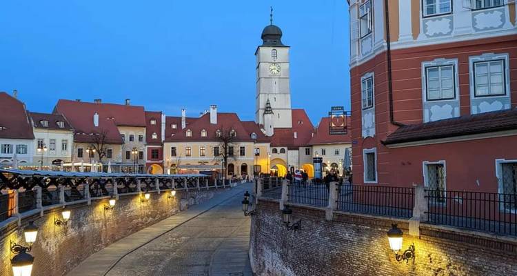 Luces nocturnas a lo largo del puente histórico y los edificios en tonos pastel del casco antiguo de Sibiu