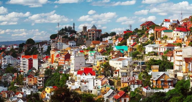 Un vivido conjunto de edificios multicolores apilados a lo largo de colinas ondulantes bajo un cielo brillante en Antananarivo.