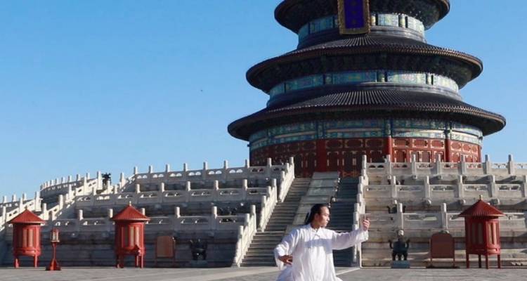 Een martial artist beoefent tai chi voor de Tempel van de Hemel's Gebedshal onder een heldere hemel.