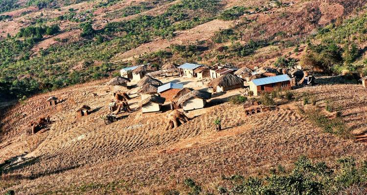 Luftaufnahme eines kleinen ländlichen Dorfes in Malawi mit Strohhütten auf einer terrassierten Hanglage
