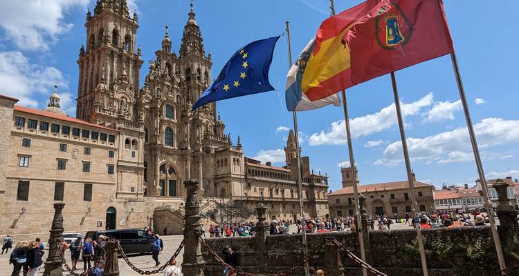 Menigten verzamelen zich voor de sierlijke gevel van de Santiago de Compostela Kathedraal terwijl EU- en Spaanse vlaggen wapperen.