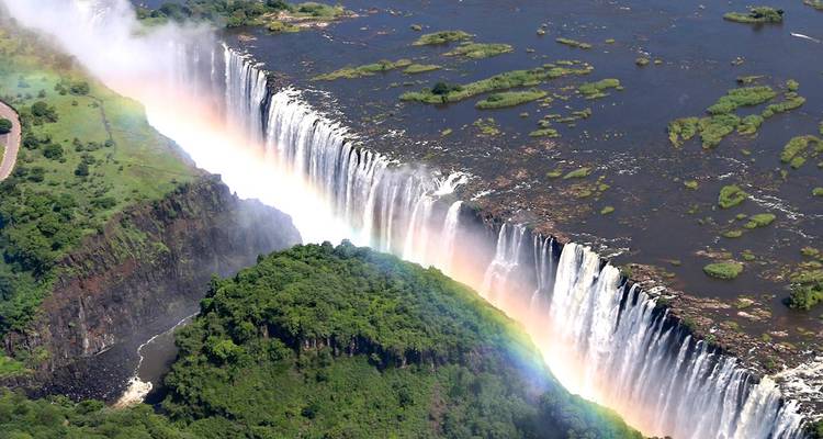 Spectacular aerial view of Victoria Falls with rainbow arcing across the plunging water.
