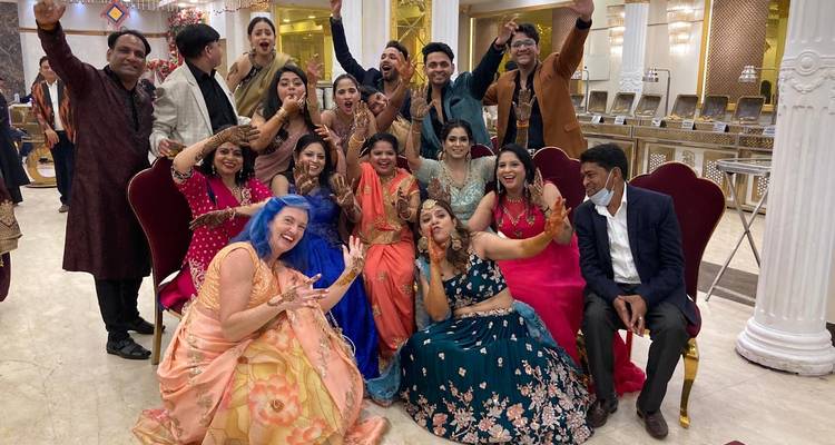 Grote feestelijke groep in kleurrijke kleding die binnenshuis poseert tijdens een Indiaas huwelijksfeest.