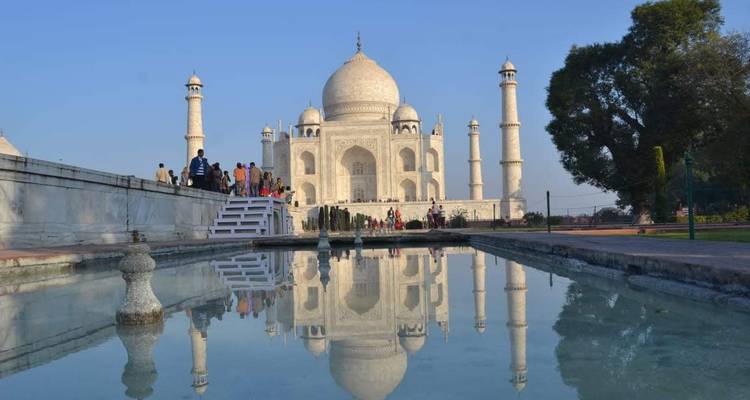 Klassiek ansichtkaartje van de Taj Mahal die zich weerspiegelt in het lange bassin onder heldere blauwe lucht.