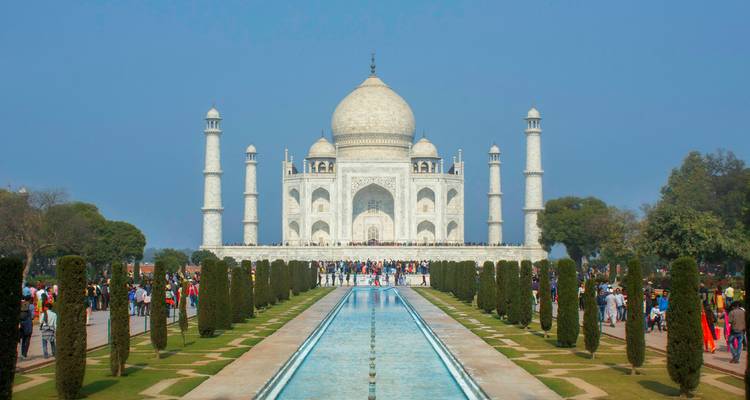 Frontaal uitzicht langs de waterloop naar de Taj Mahal met menigten in de tuinen.