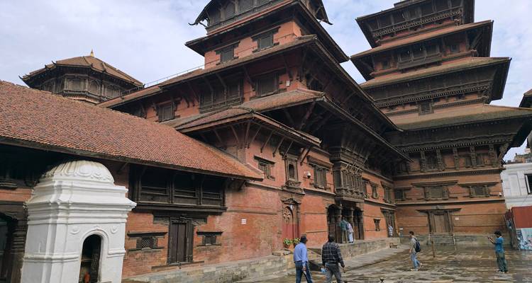 Edificios históricos de palacio de ladrillo en la Plaza Durbar de Katmandú con visitantes caminando sobre piedra mojada