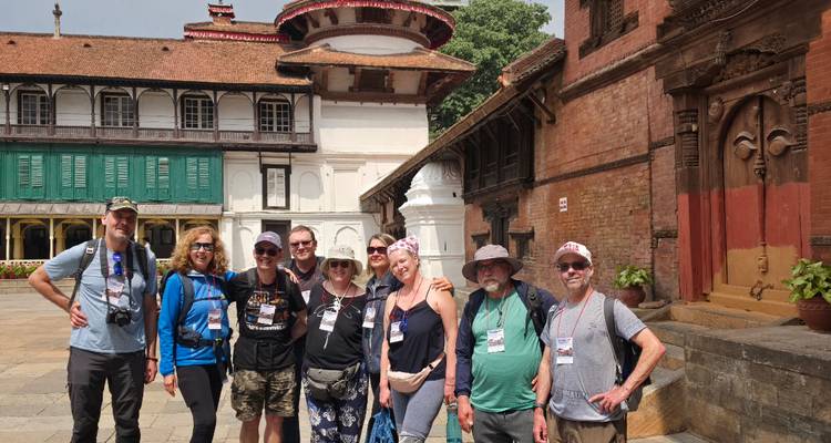Grupo de viajeros felices posando para una foto en un patio histórico de Katmandú