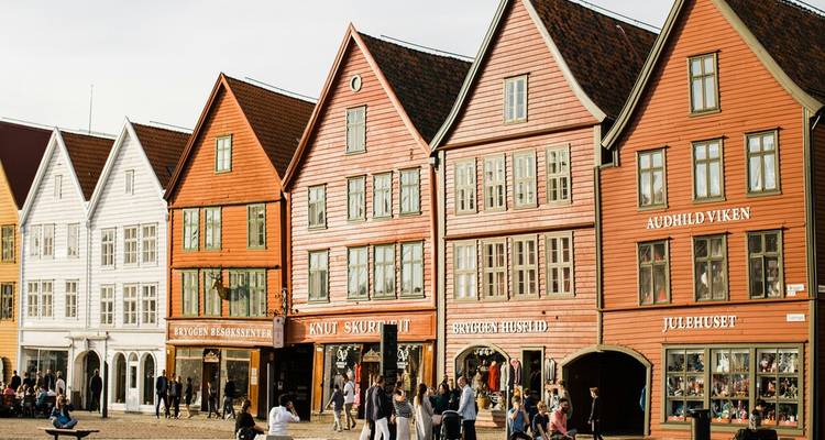 Escena a nivel del suelo de los coloridos edificios de madera de Bryggen con turistas paseando por la plaza.