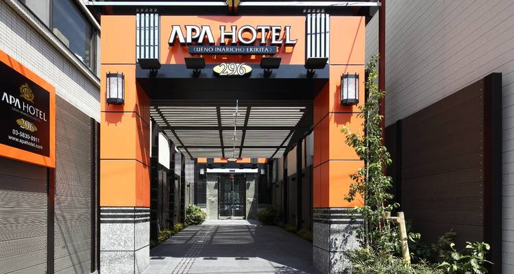 Eingangsüberdachung des orange-schwarzen APA Hotel Ueno mit moderner Beschilderung und Topfpflanzen.