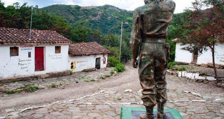 Vista trasera de una estatua de bronce de un soldado frente a un callejón rústico del pueblo