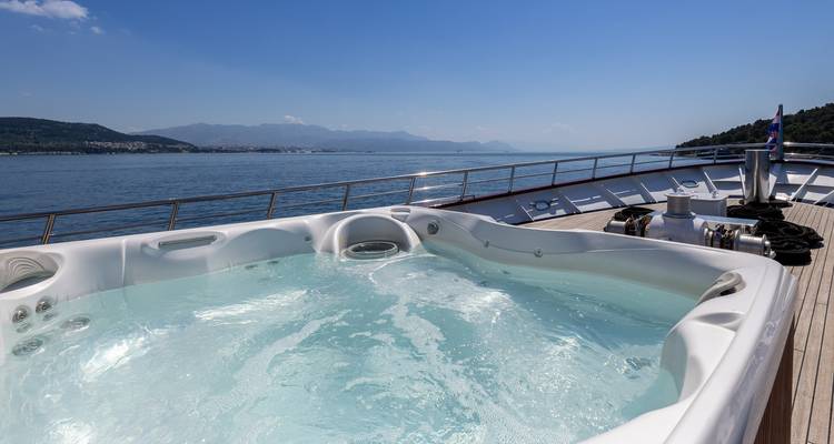 Nahaufnahme von sprudelndem Whirlpoolwasser auf dem Deck eines Schiffes mit Küstengebirgen in der Ferne.