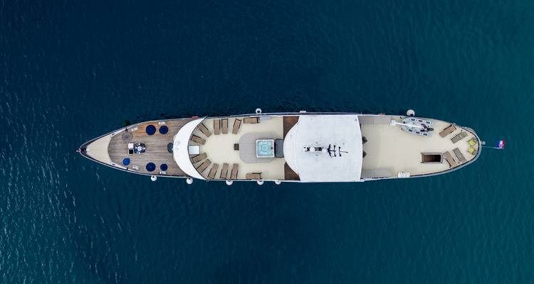 Vue aérienne de drone de haut en bas d'un yacht de luxe mettant en évidence l'aménagement du pont au-dessus d'une eau bleu profond