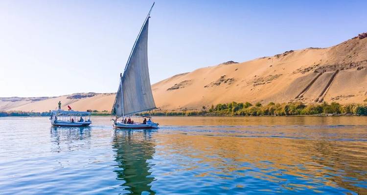 Traditionele zeilboot glijdt langs woestijnduinen die zich spiegelen in het rustige water van de Nijl