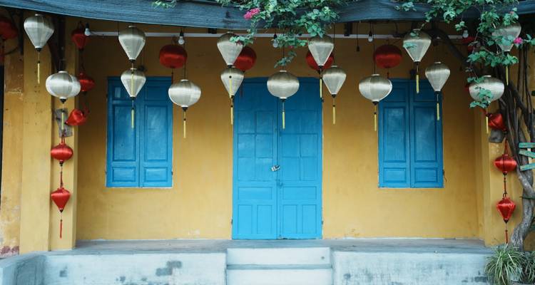 Neatly arranged silver and red lanterns hanging above bright blue double doors on a yellow wall.