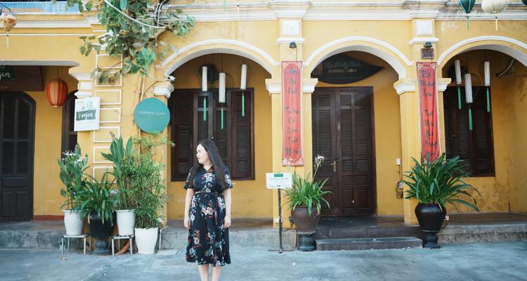 Traveler posing in front of an ornate yellow French-colonial building with arched doorways.