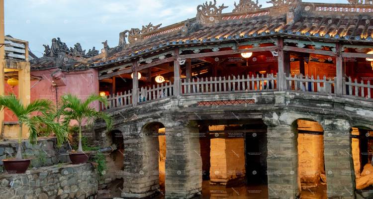 Historic Japanese Covered Bridge in Hoi An illuminated at dusk, obscured by repeated watermarks.