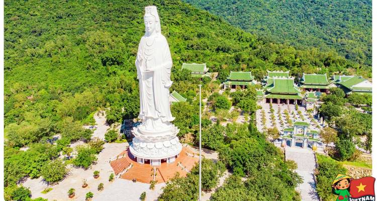 Vue aérienne de la géante statue blanche de Bouddha observant les collines verdoyantes avec une marque de dessin animé dans le coin.
