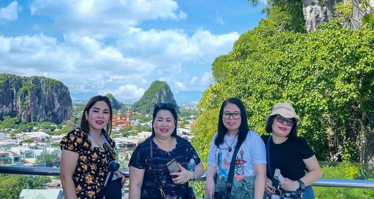 Groupe de quatre femmes souriantes à un point de vue montagneux avec un paysage karstique luxuriant en arrière-plan.