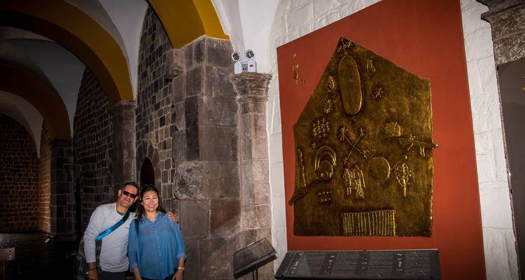 Les visiteurs se tiennent près d'une exposition d'artefacts Inca dorés à l'intérieur d'un couloir historique faiblement éclairé.