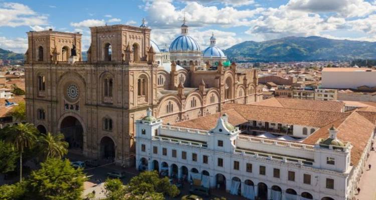 Luftaufnahme der Neuen Kathedrale von Cuenca mit blauen Kuppeln, umgeben von roten Ziegeldächern und Bergen