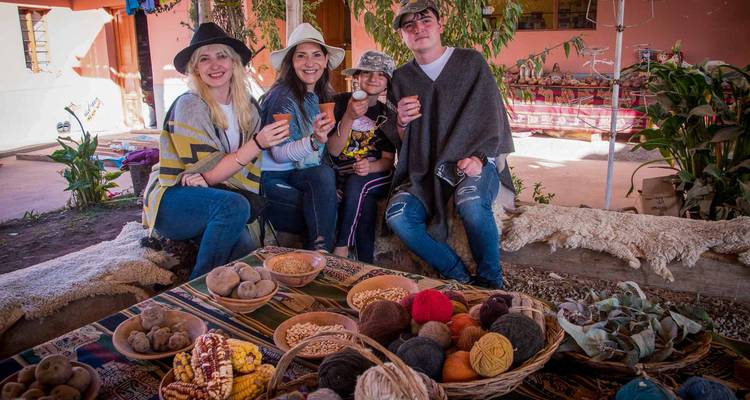 Les visiteurs apprécient les boissons traditionnelles aux côtés de paniers de pommes de terre, de maïs et de fils de couleur vive à un marché d'artisanat andin.