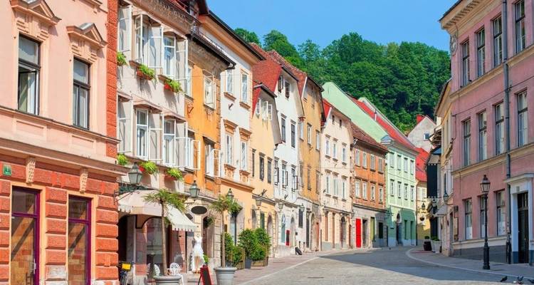 Kleurrijke historische gevels sieren een rustige kaseistraat in het oude centrum van Ljubljana onder een blauwe hemel.