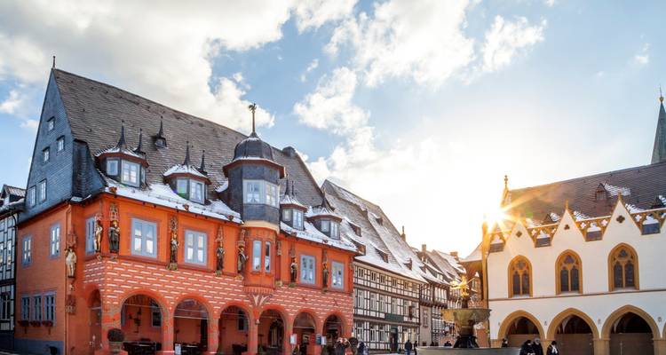 Snow-dusted half-timbered houses frame a quaint German town square under a bright winter sky.